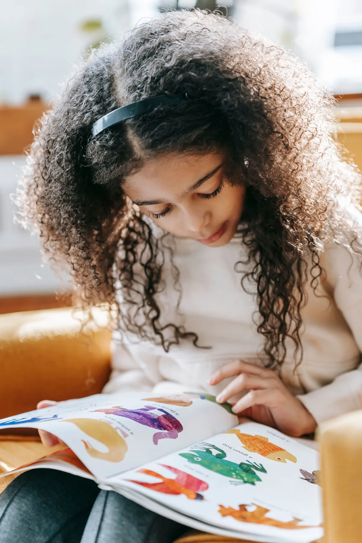 A young child reading a picture book in a warm home setting