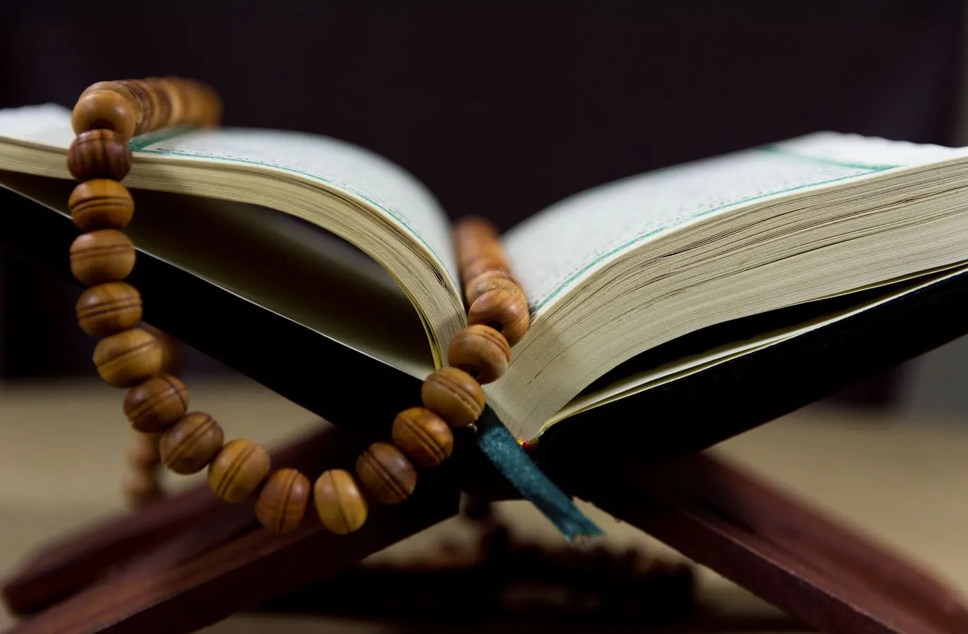 An open Quran with wooden prayer beads on a Quran stand